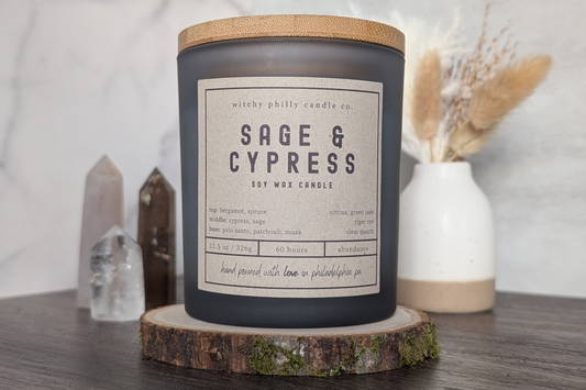 sage and cypress candle on a wood slice with crystals and pampas grass in the background