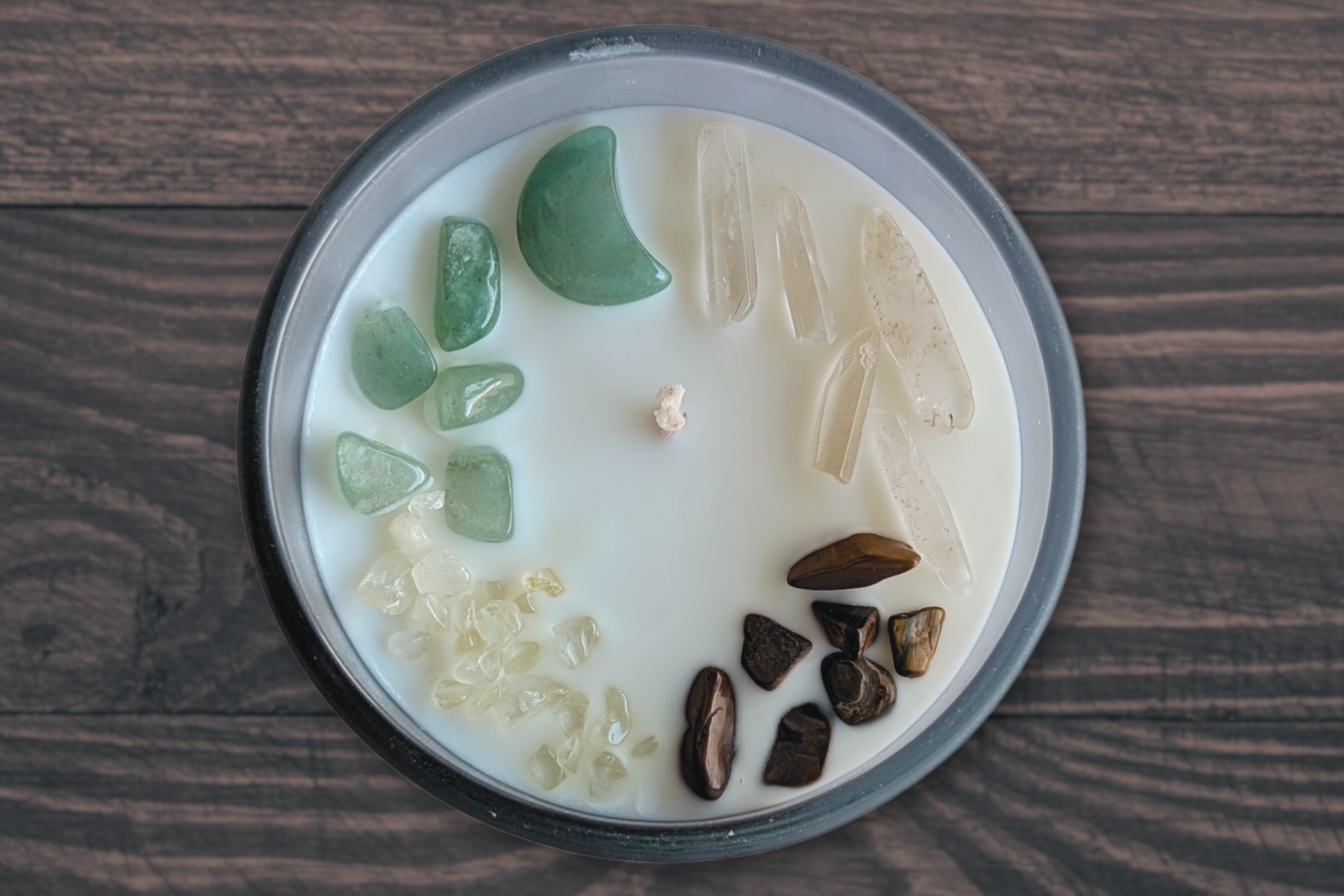 green jade, citrine, tiger eye, and clear quartz crystals on a sage and cypress candle